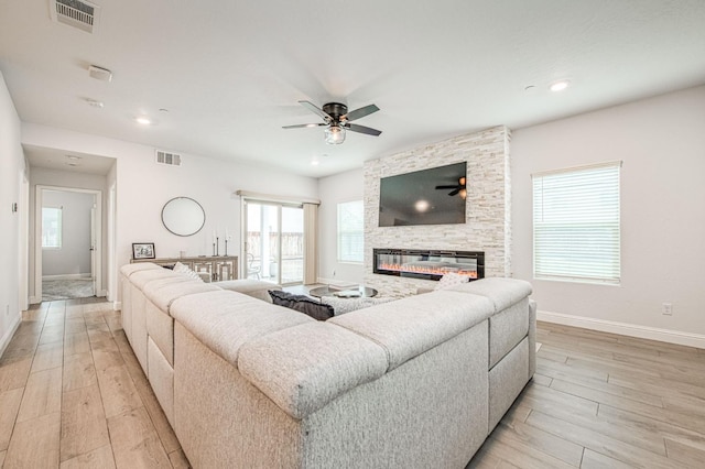 living area featuring visible vents, baseboards, light wood-style floors, and a fireplace