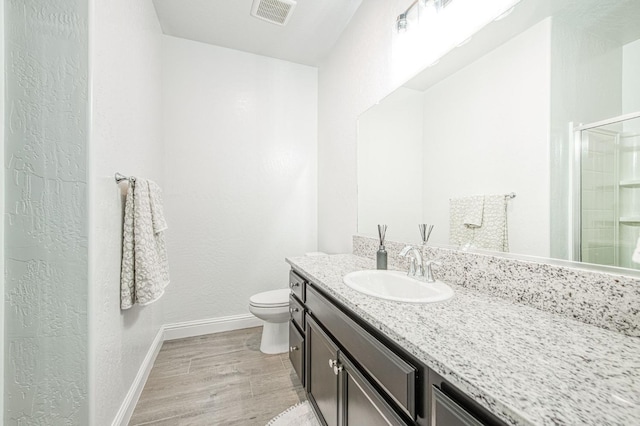 bathroom with visible vents, toilet, a stall shower, wood finished floors, and vanity