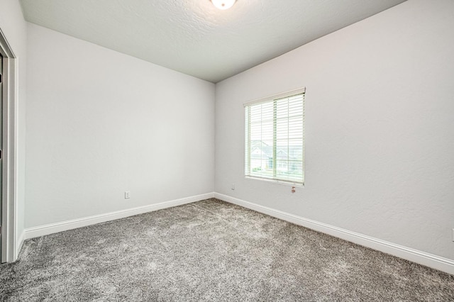 carpeted empty room with baseboards and a textured ceiling