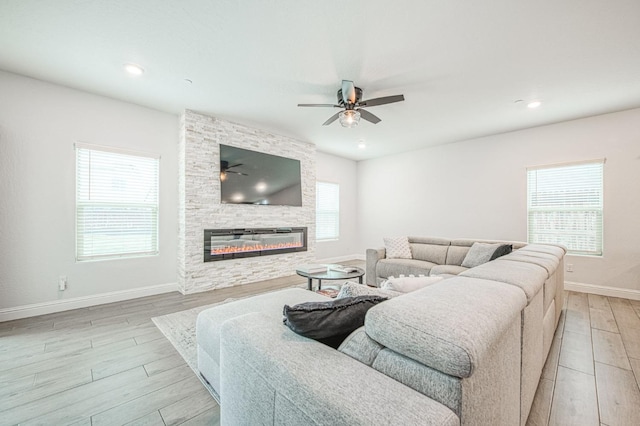 living room featuring a fireplace, a healthy amount of sunlight, light wood-type flooring, and baseboards