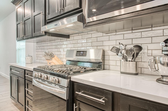 kitchen with light wood-style flooring, under cabinet range hood, backsplash, appliances with stainless steel finishes, and light stone countertops