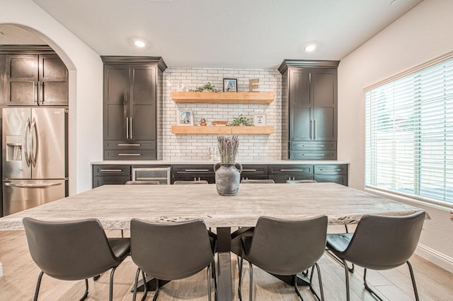 dining space with recessed lighting, baseboards, arched walkways, and light wood-style flooring