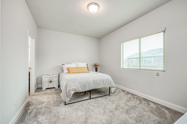 carpeted bedroom featuring baseboards and a textured ceiling