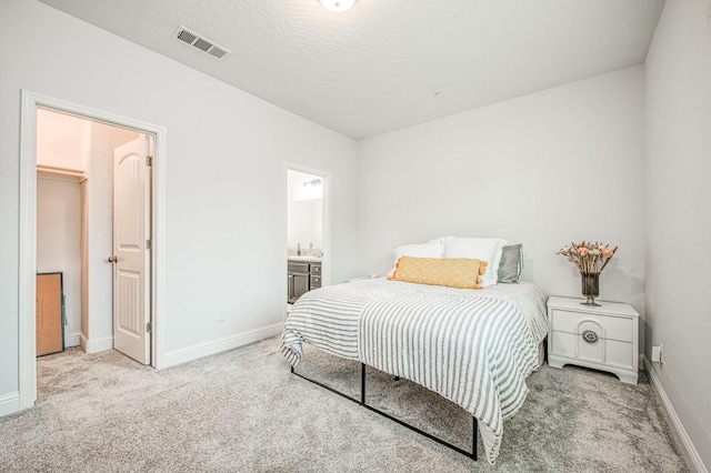 bedroom featuring carpet, visible vents, baseboards, a spacious closet, and ensuite bathroom