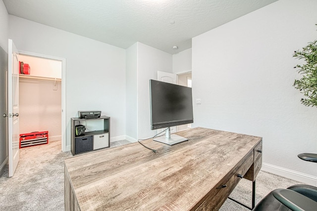 office space featuring light colored carpet, a textured ceiling, and baseboards