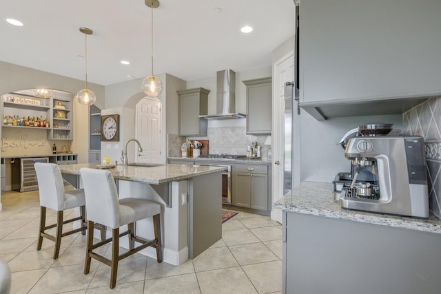 kitchen with decorative backsplash, wine cooler, wall chimney exhaust hood, and gray cabinetry