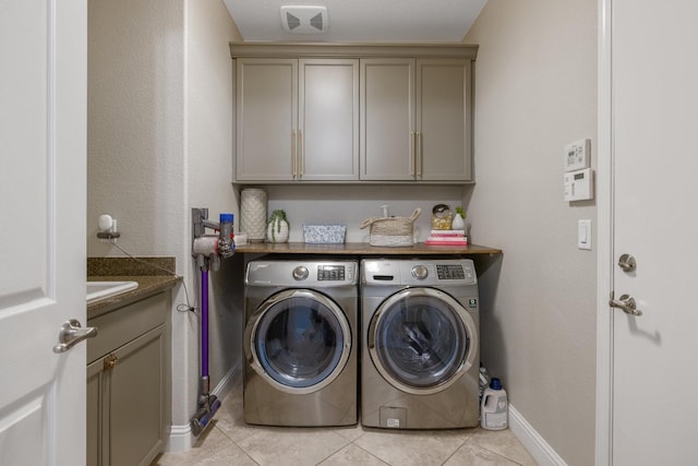 clothes washing area featuring light tile patterned flooring, cabinet space, independent washer and dryer, and baseboards