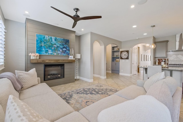 living room with recessed lighting, arched walkways, light tile patterned flooring, and a fireplace