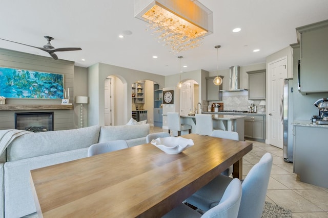 dining room featuring a large fireplace, recessed lighting, light tile patterned flooring, arched walkways, and a ceiling fan