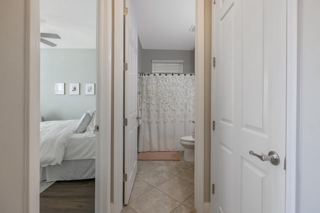 full bath with toilet, ensuite bathroom, curtained shower, tile patterned flooring, and ceiling fan