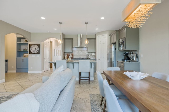 dining room featuring built in shelves, baseboards, light tile patterned floors, recessed lighting, and arched walkways