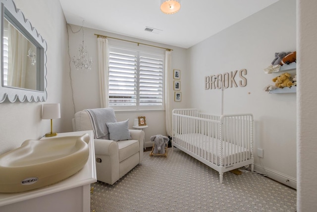 bedroom with visible vents, a crib, baseboards, and carpet floors