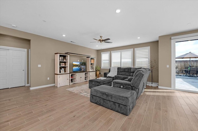 living area with recessed lighting, a ceiling fan, light wood-type flooring, and baseboards