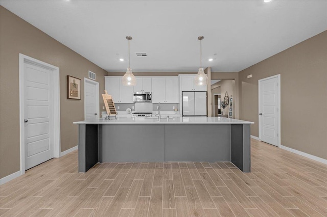 kitchen with visible vents, stainless steel microwave, a spacious island, white cabinets, and white refrigerator