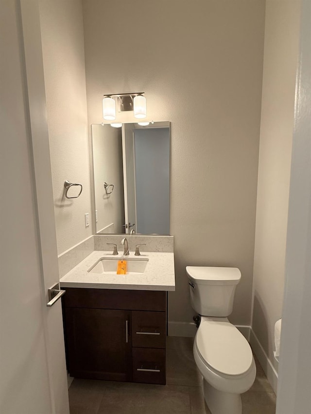 bathroom featuring toilet, vanity, and baseboards