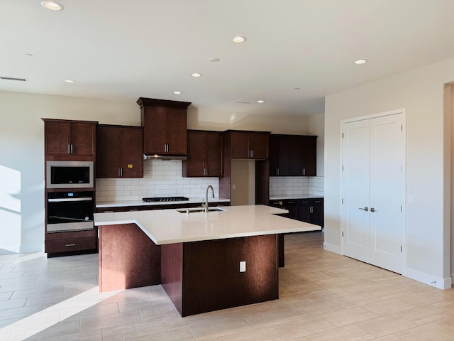 kitchen featuring visible vents, an island with sink, a sink, stainless steel appliances, and light countertops