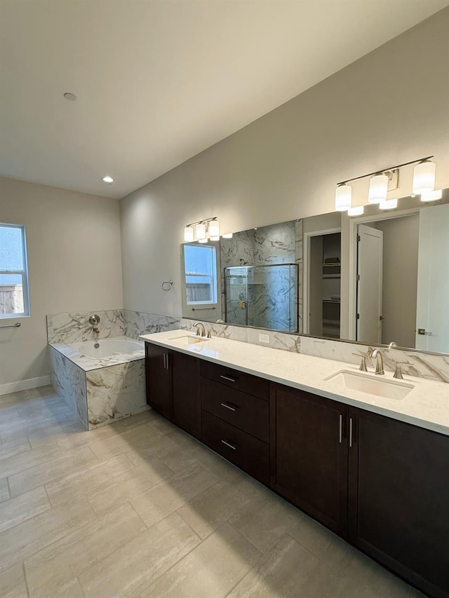 bathroom with double vanity, a garden tub, a marble finish shower, and a sink