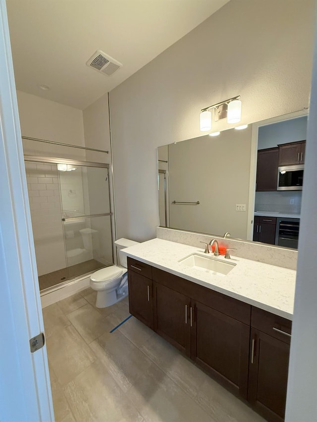 bathroom featuring visible vents, wine cooler, toilet, a stall shower, and vanity