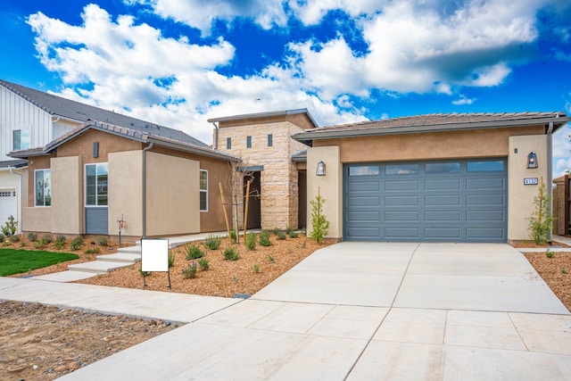 view of front of home with stone siding, stucco siding, an attached garage, and driveway