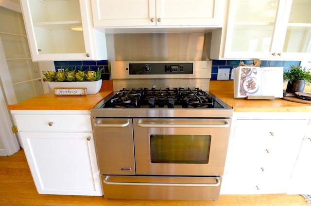 kitchen with range with two ovens, tasteful backsplash, and white cabinets