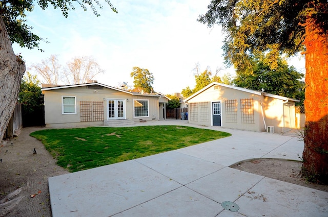 view of front facade with a front lawn, fence, concrete driveway, an outbuilding, and a patio