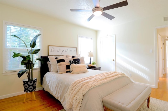 bedroom with visible vents, a ceiling fan, baseboards, and wood finished floors