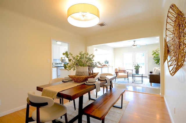 dining space with light wood-style flooring, baseboards, and visible vents