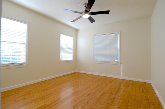 unfurnished room featuring plenty of natural light, a ceiling fan, light wood-type flooring, and baseboards