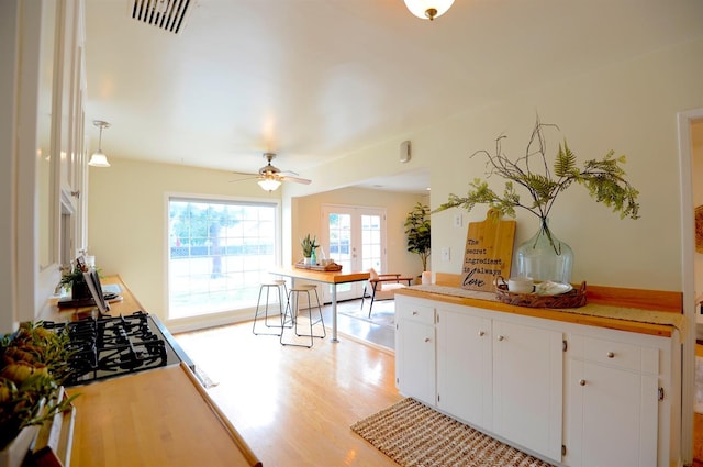 kitchen with visible vents, light wood finished floors, white cabinetry, french doors, and light countertops