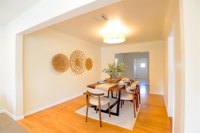 dining area with light wood-type flooring, baseboards, and visible vents