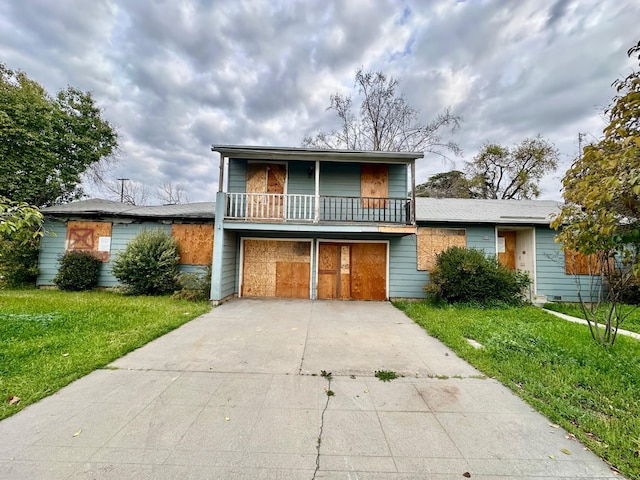 view of front of home featuring a front lawn, a balcony, concrete driveway, and a garage