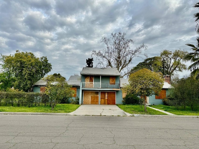 view of front of home featuring a garage, driveway, a front lawn, and a balcony