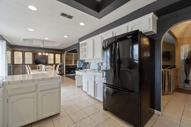 kitchen with visible vents, open shelves, white cabinetry, freestanding refrigerator, and arched walkways