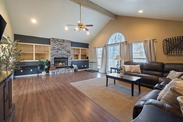 living room with beam ceiling, high vaulted ceiling, dark wood-style floors, a fireplace, and ceiling fan