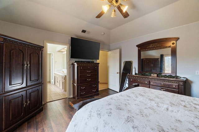 bedroom with visible vents, ensuite bathroom, a ceiling fan, dark wood finished floors, and vaulted ceiling