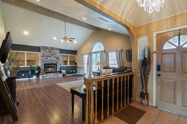 entrance foyer with beamed ceiling, a fireplace, wood finished floors, arched walkways, and a textured ceiling