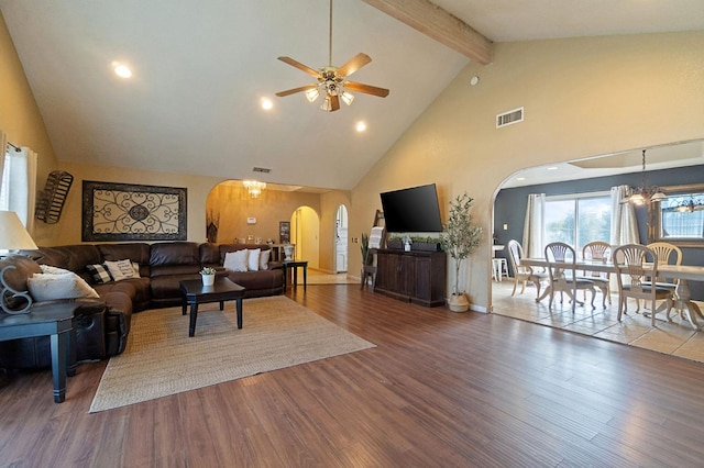 living area with wood finished floors, arched walkways, visible vents, and beam ceiling