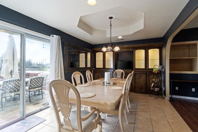 dining room featuring light tile patterned floors, an inviting chandelier, and a tray ceiling