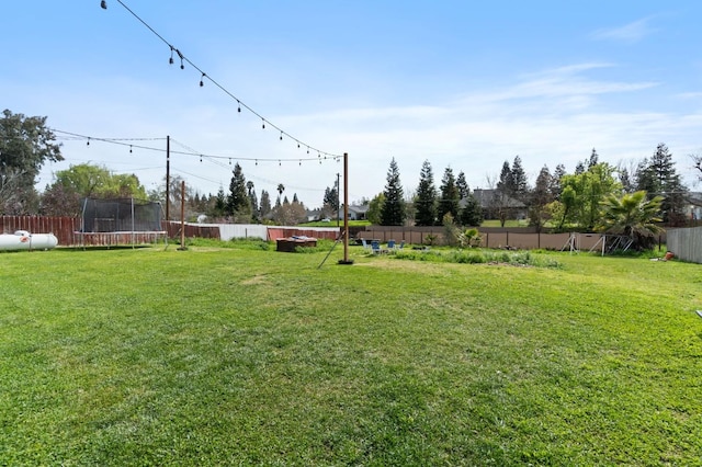 view of yard with a trampoline and a fenced backyard