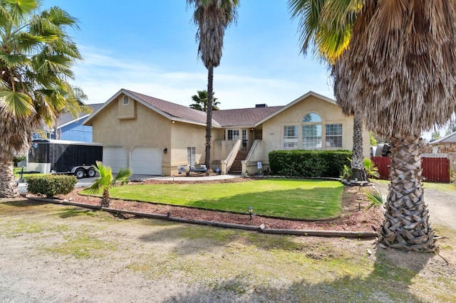 view of front of house featuring stucco siding, a garage, a front yard, and fence