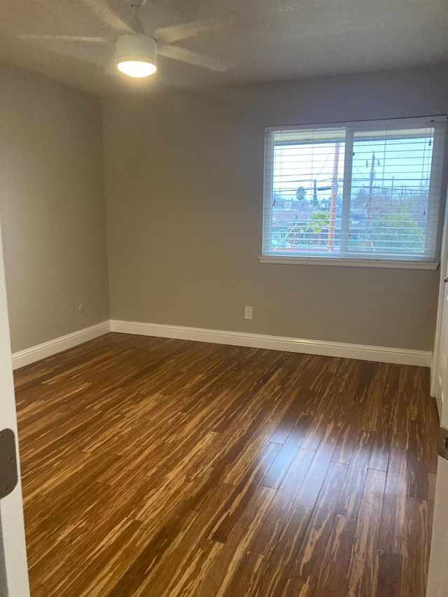 spare room with dark wood finished floors and baseboards