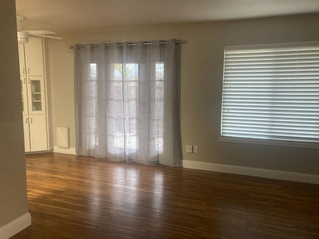 empty room featuring a wealth of natural light, baseboards, and wood finished floors