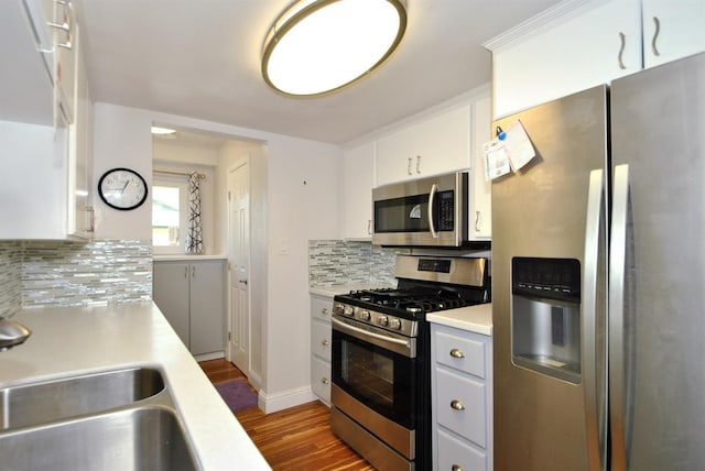 kitchen featuring wood finished floors, a sink, stainless steel appliances, light countertops, and backsplash