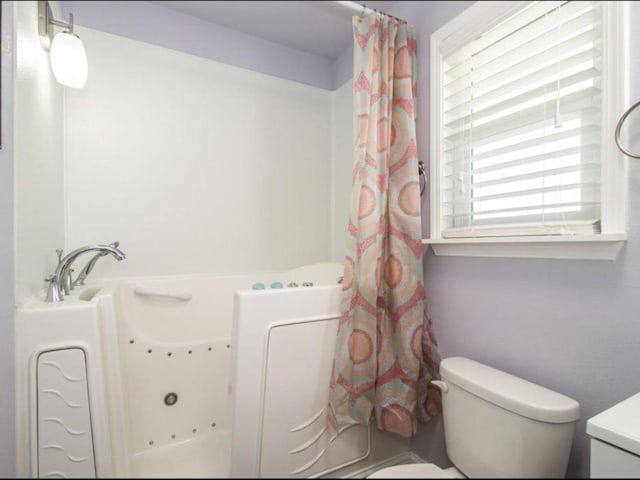 bathroom featuring a jetted tub and toilet