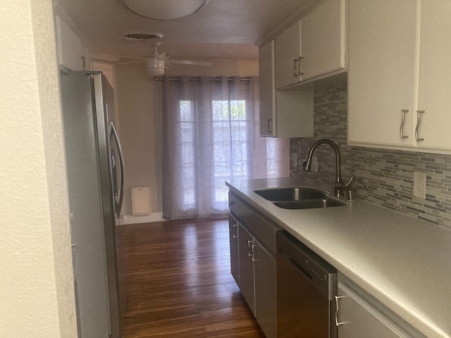 kitchen featuring a sink, light countertops, decorative backsplash, stainless steel appliances, and dark wood-style flooring