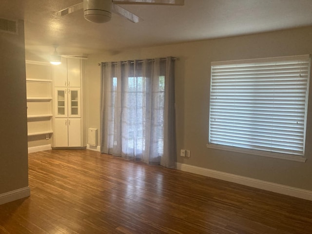 unfurnished room featuring visible vents, baseboards, ceiling fan, and wood finished floors