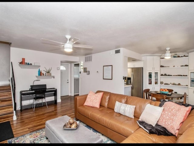 living room featuring visible vents, stairway, a ceiling fan, and wood finished floors