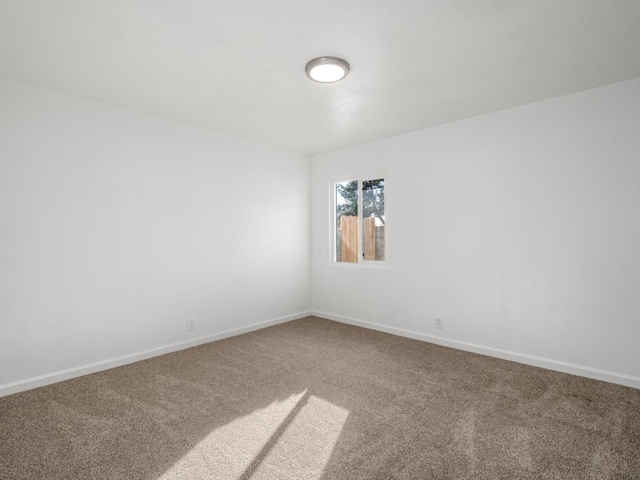 carpeted spare room featuring baseboards