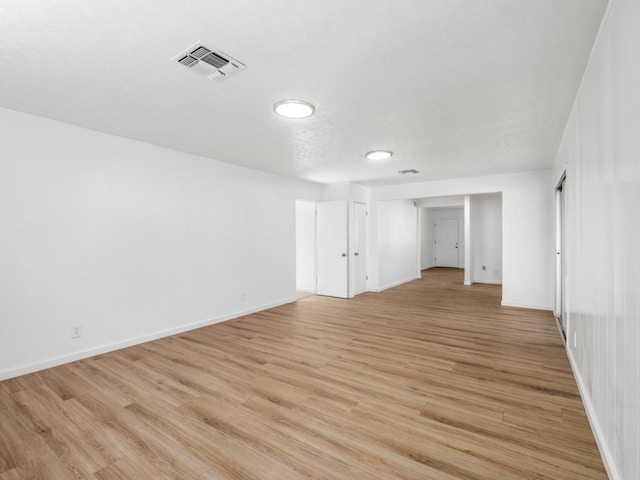 empty room with visible vents, baseboards, and light wood finished floors