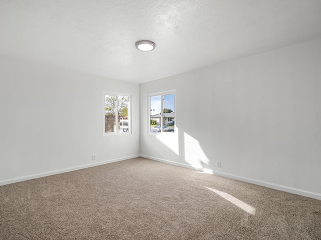 spare room featuring a textured ceiling, baseboards, and carpet